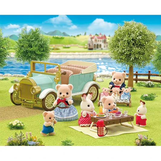 Sylvanian Families Classic Family Car parked beside a lake with animal figures enjoying a picnic at a small table near the water.