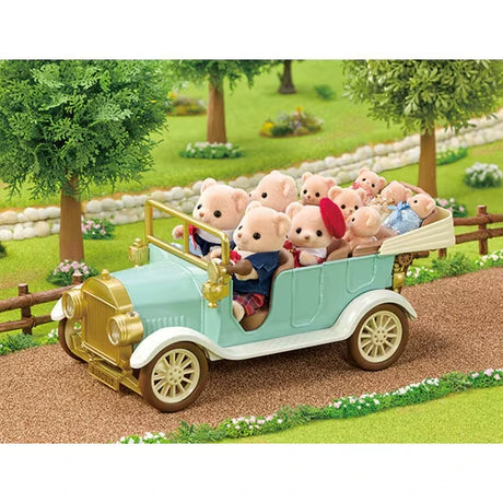 Mint green Sylvanian Families Classic Family Car carrying several animal passengers along a woodland road bordered by trees and a wooden fence.