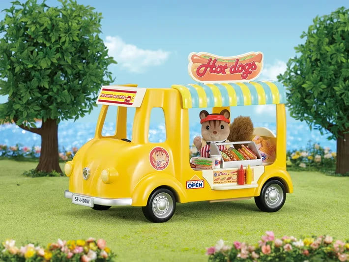 Yellow Sylvanian Families Hot Dog Van shown with trees and a Hot Dogs sign