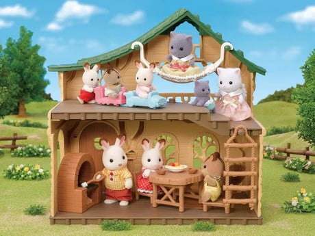 Sylvanian Families animal figures gathered inside the open Lakeside Lodge, with figures dining downstairs and others upstairs beside the hammock and ladder.
