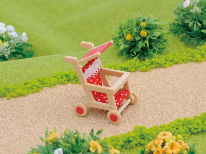 Sylvanian Families red pushchair on village path with garden background