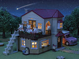 Sylvanian Families Red Roof Country Home shown at night with lights visible inside and animal figures around the house