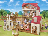 Open Sylvanian Families Red Roof Country Home shown in a garden scene with animal figures and accessories