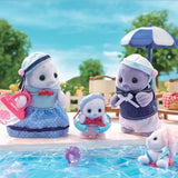 Sylvanian Families Seal Family gathered beside a swimming pool, featuring the mother carrying a pink beach bag, the father in his navy sailor outfit, a baby wearing a swimming ring and another baby beside the water.