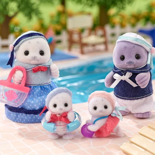 Four Sylvanian Families Seal Family figures arranged beside a swimming pool, showing their blue and pink sailor outfits, pink beach bag, transparent blue swimming ring and purple beach ball.