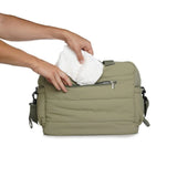 Thermobaby Pluméa Cactus Green changing bag with hand placing white nappies into the front pocket