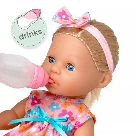 Close view of the Tiny Tears Classic doll drinking from the pink bottle, with long blonde hair, floral headband and floral dress