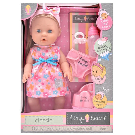 Front of the Tiny Tears Classic Crying & Wetting with Hair box showing the 38 cm blonde doll, floral dress, bottle, dummy, pull up underwear, potty and crying, drinking, wetting and sleeping eyes feature graphics