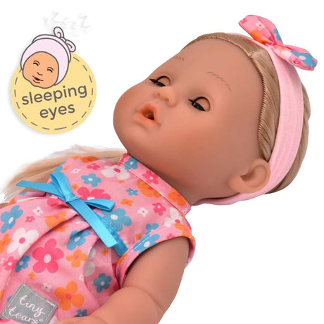 Tiny Tears Classic doll lying down with her sleeping eyes closed, long blonde hair, pink floral headband and floral dress