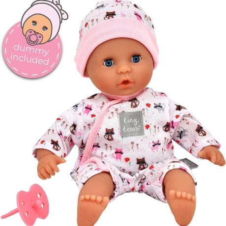 Tiny Tears Teeny Baby sitting upright in a pink trimmed cat print outfit and matching hat, with blue eyes and the included pink dummy shown beside the doll