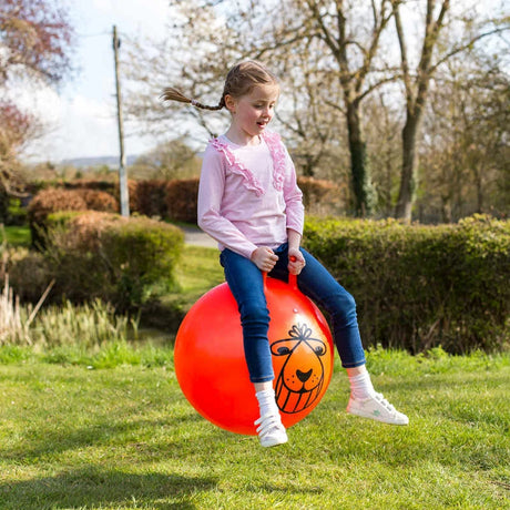 Child seated on orange Tobar Retro Space Hopper outdoors