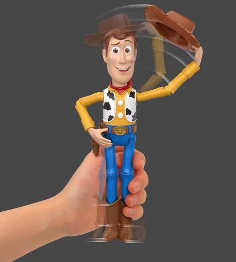 Hand holding Woody figure with hat tipping motion shown on a grey background