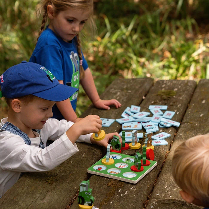 Child placing a wooden Tractor Ted game piece onto the Tic Tac Toe board
