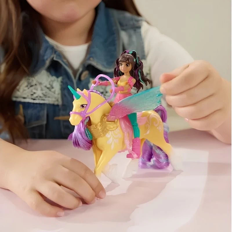 Child using both hands to play with Unicorn Academy Ava riding Leaf on a white table, showing the doll's pink outfit and the unicorn's translucent turquoise wings, yellow body and purple mane.