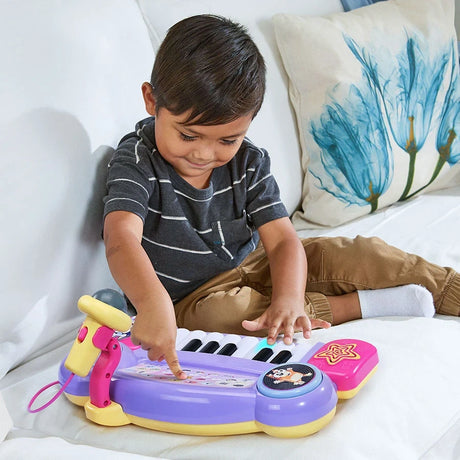 Child pressing the controls and piano keys on the VTech Bluey Sing-Along Keyboard while seated on a sofa