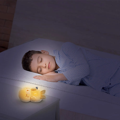 Child in bed beside a glowing VTech Calming Lights Otter on a bedside table