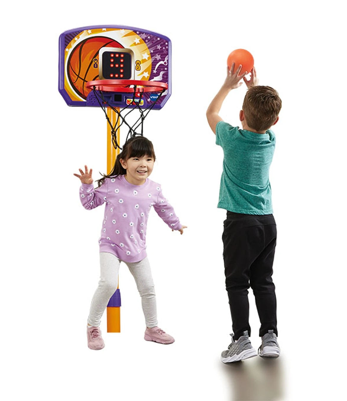 Two children playing with the VTech Counting Hoops Basketball Stand, one shooting the orange ball while the other stands beside the hoop