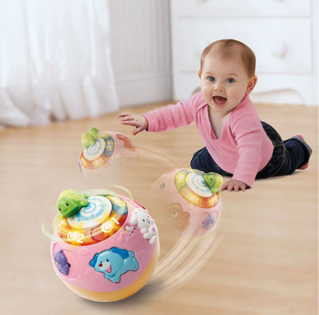 Baby wearing pink top crawling on wooden floor reaching toward pink VTech Crawl and Learn Bright Lights Ball with green turtle on top and light up number buttons