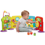 Baby sitting in front of the VTech Discovery Play Centre and reaching towards its yellow steering wheel, with three colourful shape sorting blocks on the floor.
