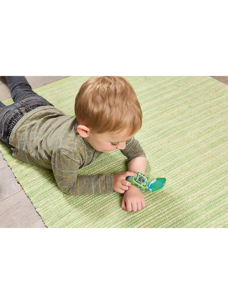 Child wearing VTech Disney Pixar Toy Story 5 Buzz Lightyear Learning Watch on wrist while lying on green rug