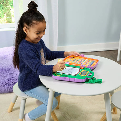 Child using VTech Dora Learning Backpack, writing on screen with stylus at a table – Ireland.