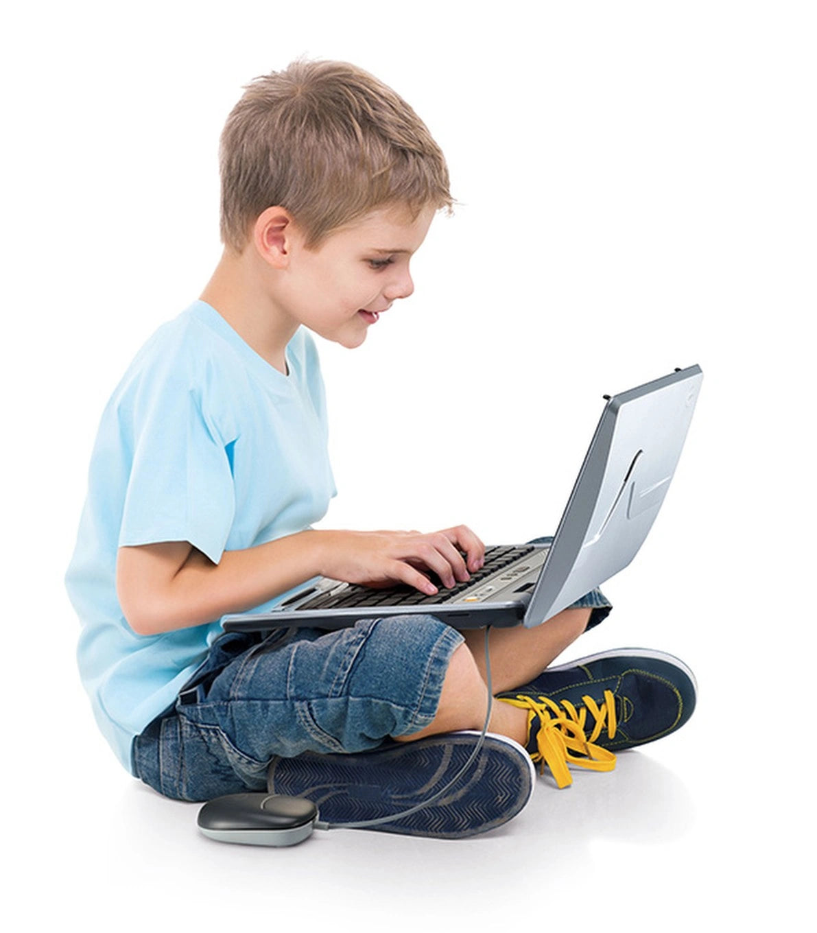 Boy sitting cross legged and typing on a VTech Genio MAX My First Laptop with the wired mouse beside him
