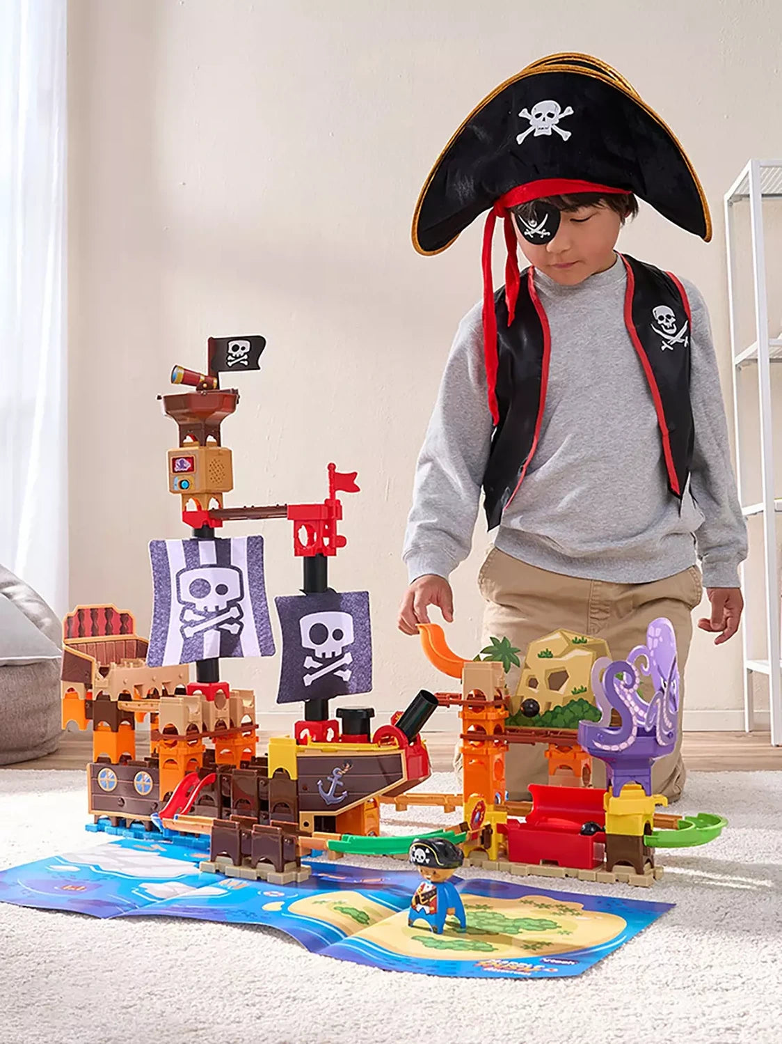 Child wearing a pirate hat beside the VTech Marble Rush Adventures Pirate Ship with assembled marble track and octopus vortex