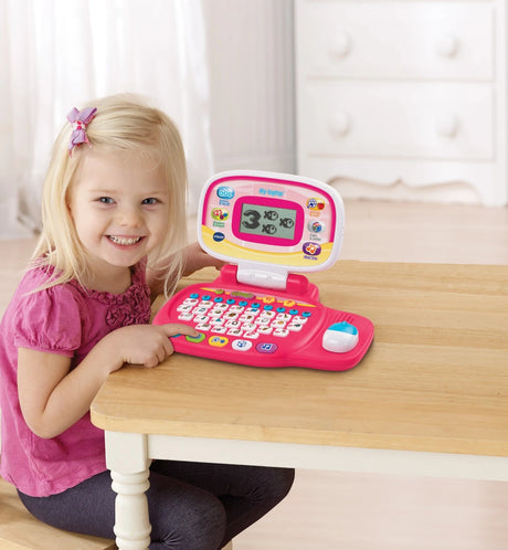 Child sitting at a table using VTech My Laptop Pink open in front of her