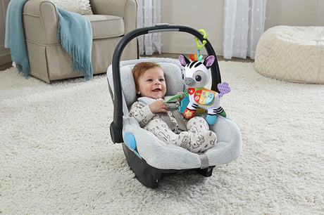 Baby in carrier with VTech On-the-Go Soft Zebra attached to the handle