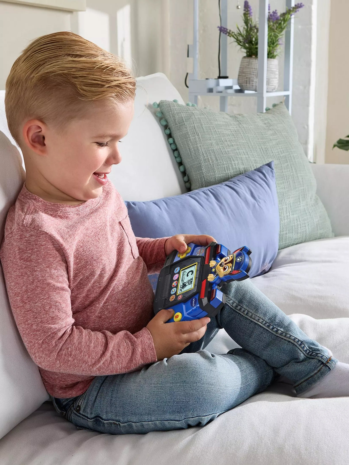 Child seated on a sofa playing with the VTech PAW Patrol Chase Game & Go
