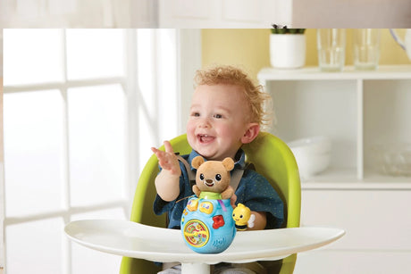 Child in highchair with VTech Peek-a-Boo Bear toy on the tray
