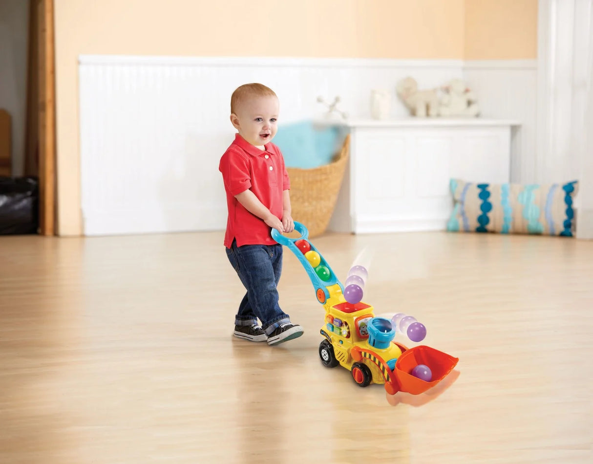 Smiling toddler pushing the VTech Pop and Drop Digger as balls pop from the chute during playtime in Ireland