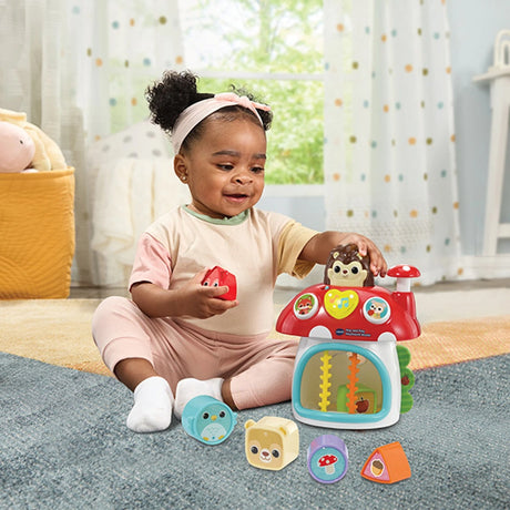 Child sitting beside VTech Pop and Play Mushroom House with six shape blocks