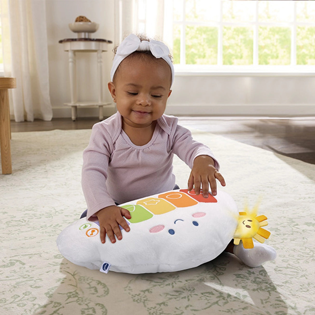 Child seated on the floor pressing the colourful keys on the VTech Rainbow Cloud Piano