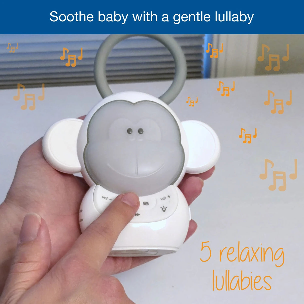 Hand pressing the VTech Myla the Monkey Portable Soother controls with a 5 relaxing lullabies graphic
