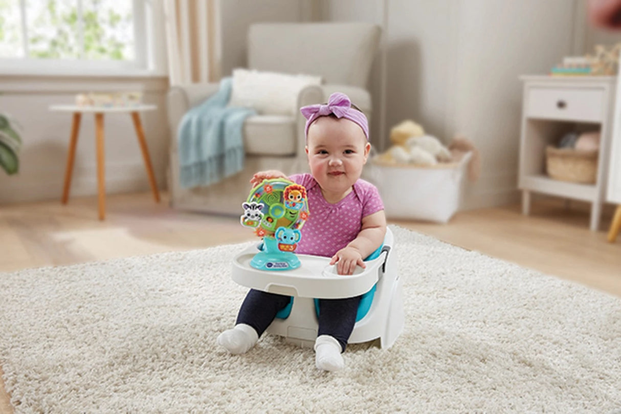 Child seated in a floor seat with the VTech Sing-Along Spinning Wheel attached to the tray 