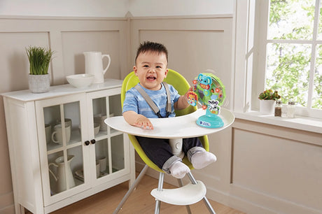 Child seated in a highchair with the VTech Sing-Along Spinning Wheel attached to the tray