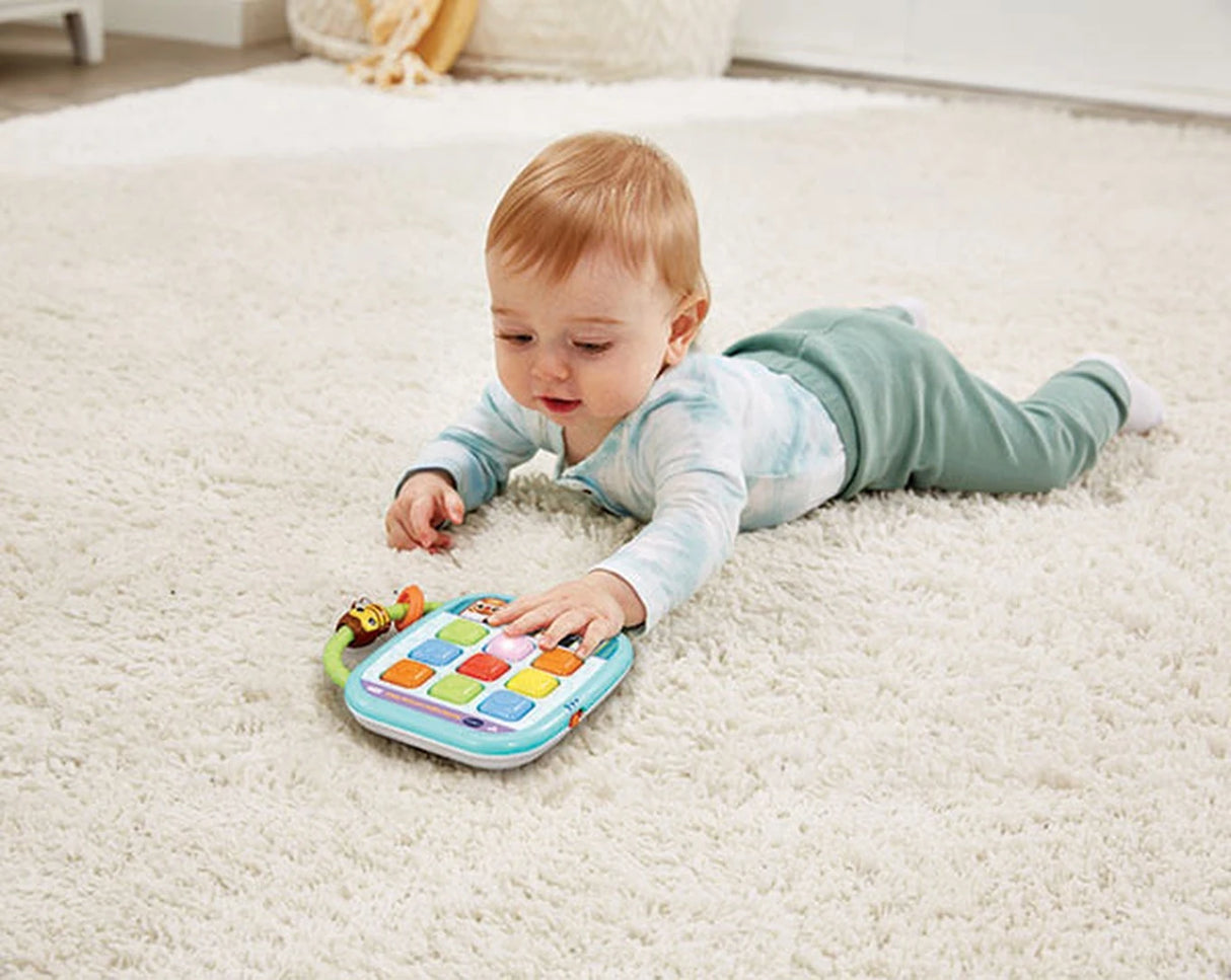 Baby lying on a rug with VTech Squishy Lights Learning Tablet