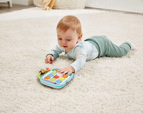 Baby lying on a rug with VTech Squishy Lights Learning Tablet