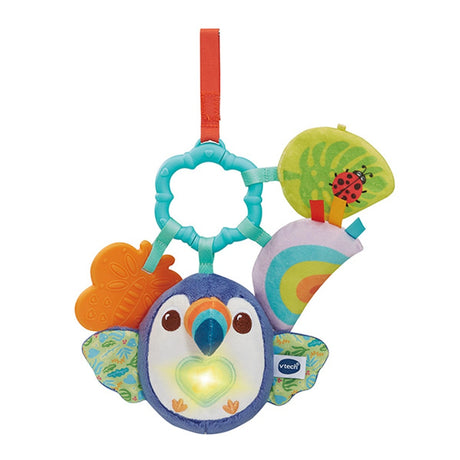 VTech Take Along Toucan front angle view showing illuminated heart button, patterned wings, soft rainbow fabric piece and textured hanging elements
