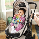 Baby sitting in stroller holding VTech Take Along Toucan toy attached by strap, showing light up heart and rainbow fabric rattle