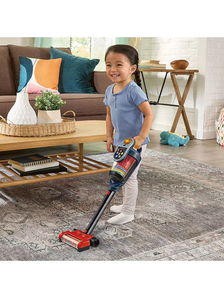 VTech Tidy Up Vacuum with a child using the stick vacuum on a patterned rug in a living room