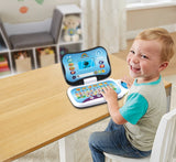Child sitting at a wooden table with VTech Toddler Tech Laptop open