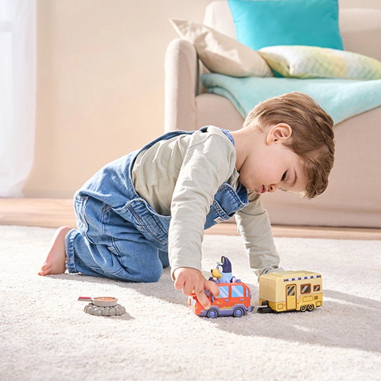 Child playing with the VTech Bluey Family Car & Caravan on a rug with the campfire and pan accessories