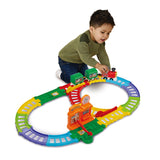 Young child kneeling on the floor playing with the Toot-Toot train set, pushing the red engine along the colourful track in front of them.