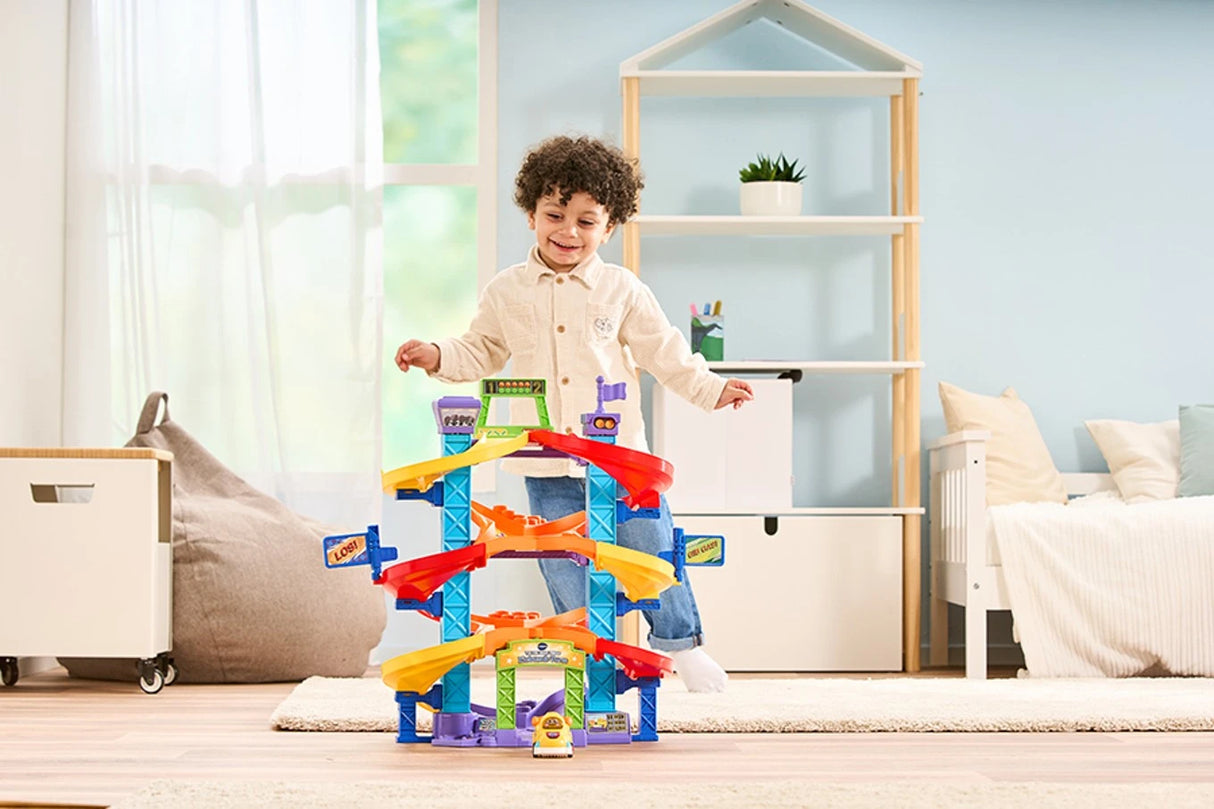 Child behind VTech Toot-Toot Drivers Criss-Cross Raceway in a bedroom with the yellow car at the front