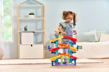Child standing and playing with VTech Toot-Toot Drivers Criss-Cross Raceway in a playroom