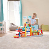 Child seated on the floor playing with the VTech Toot-Toot Drivers Roll & Repair Garage 