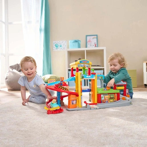 Two children playing with the VTech Toot-Toot Drivers Roll & Repair Garage on the floor