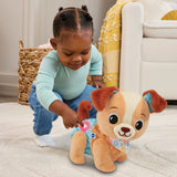 Child pressing the light up heart button on the VTech Walk & Wag Puppy plush toy